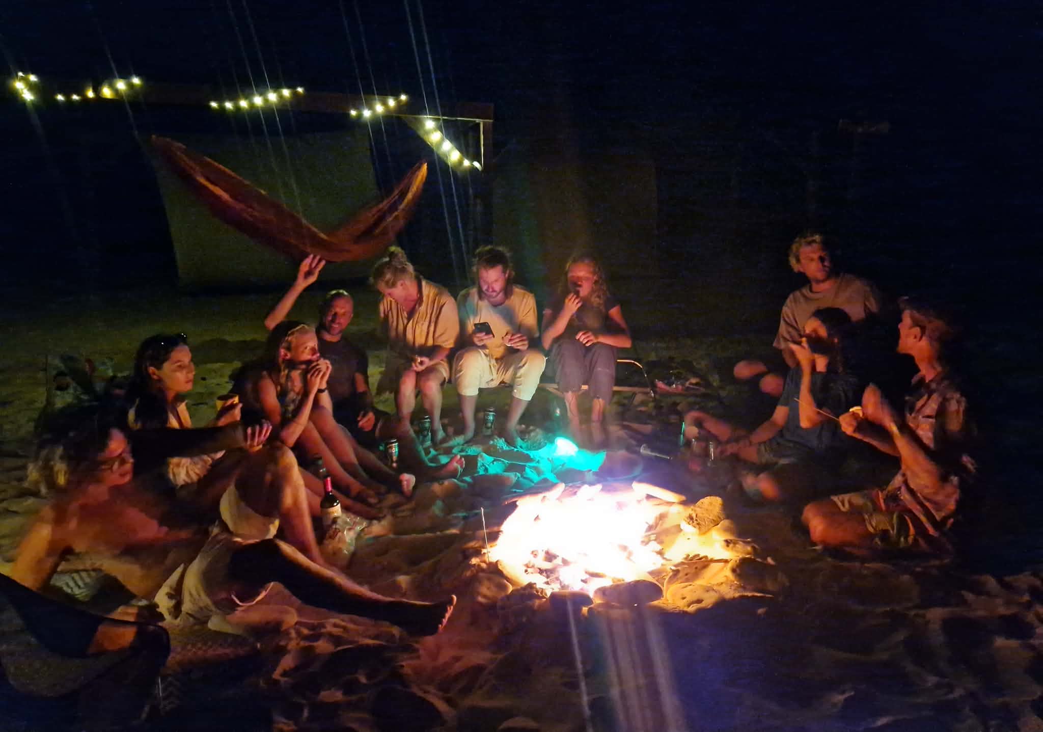 The group gathered around the bonfire on the beach after dark